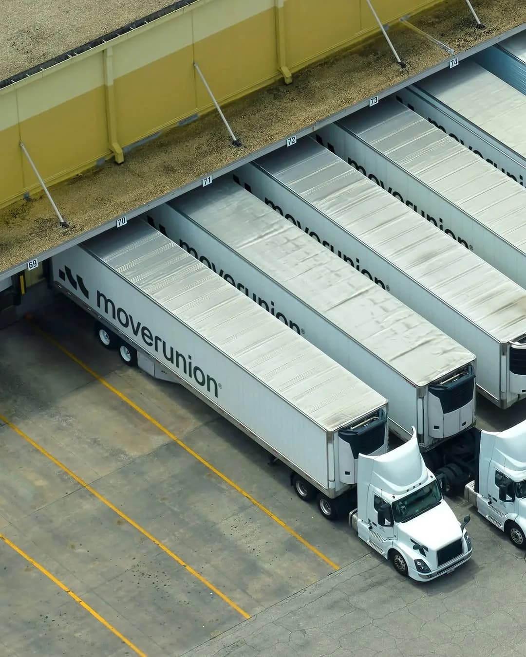Fleet of transport tractor-trailers docked at warehouse loading bays